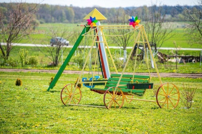 Spalvingas vaikų vežimėlis su sūpynėmis lauke